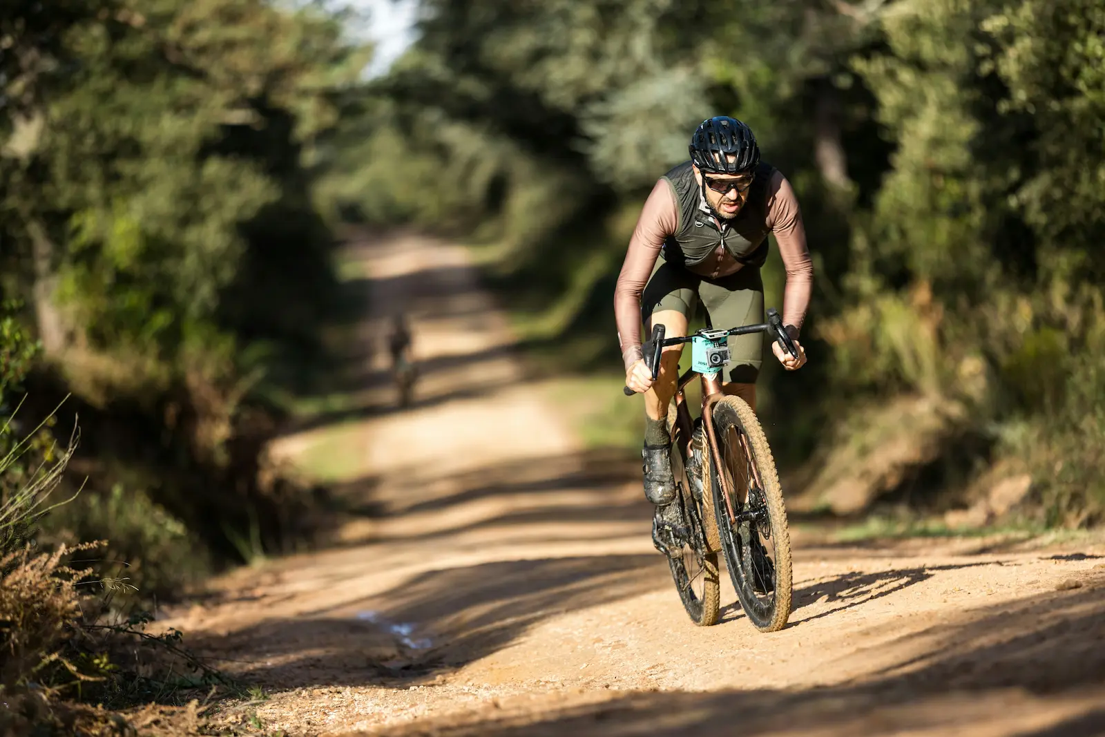 Cycliste gravel en position aérodynamique sur sentier de terre